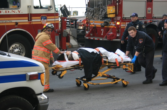 Paramedics moving a patient on a stretcher beside an ambulance