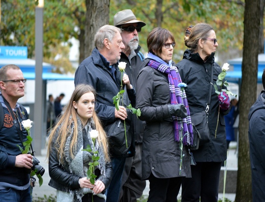 Officers and family members holding white roses at a memorial
