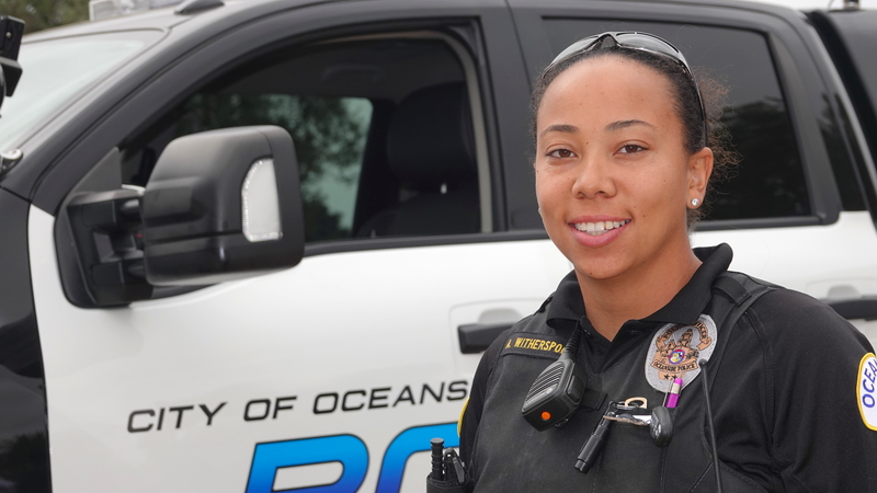 Officer standing beside a City of Oceanside patrol vehicle