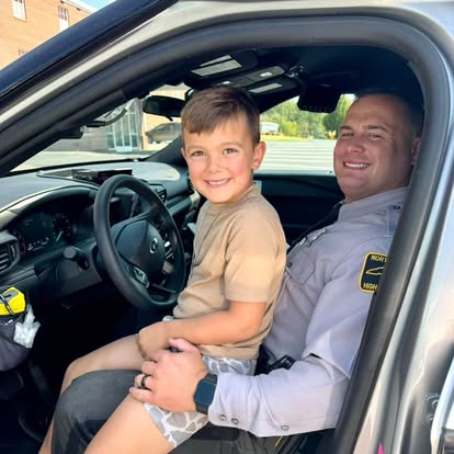 Officer seated in a patrol car with a young boy