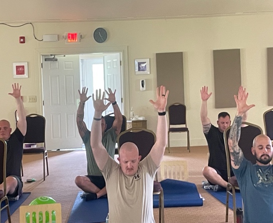 Participants in a SKY class raising their arms in a bright room